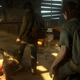 Sunlight beams into a poorly lit room as Joel steps in front of Ellie and places his foot on the shoulder of an infected and aims his gun at its head.